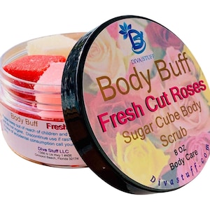 Puede incluir: Un tarro abierto de Diva Stuff Body Buff Fresh Cut Roses Sugar Cube Body Scrub. El tarro contiene cubos de azúcar rojos, rosas y blancos. La tapa muestra el nombre del producto, imágenes de rosas y "8 OZ Body Care".