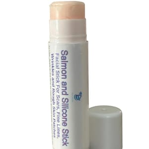 Peut inclure: Un bâton facial blanc et violet clair avec un dessus de couleur pêche. Le produit est étiqueté "Salmon and Silicone Stick" et est conçu pour les cicatrices, les ridules, les rides et les zones rugueuses. Le bouchon est détaché.