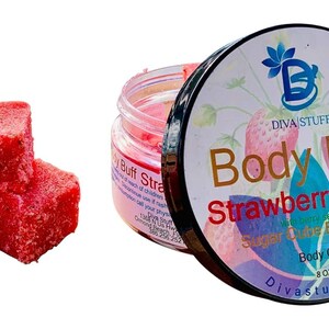 Puede incluir: Un tarro de exfoliante corporal rosa y tres cubos de exfoliante corporal rojos y cuadrados. La tapa del tarro dice "Body Buff Strawberry Fields Sugar Cube Body Scrub" con un gráfico de fresa. Los cubos son de color rojo vibrante.