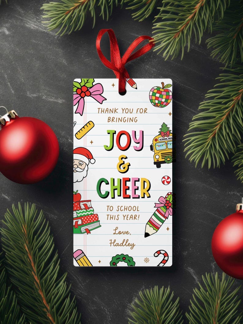 May include: A rectangular gift tag with a red ribbon, featuring colorful illustrations and text. The tag says "Thank You for Bringing Joy & Cheer to School This Year! Love, Hadley." Decorative elements include a school bus, apple, and pencil.