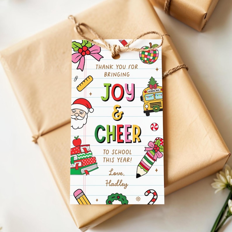 May include: A white gift tag with the words "Thank You For Bringing Joy & Cheer To School This Year! Love, Hadley" and colorful illustrations of a school bus, Santa, and a pencil, tied to a wrapped gift.
