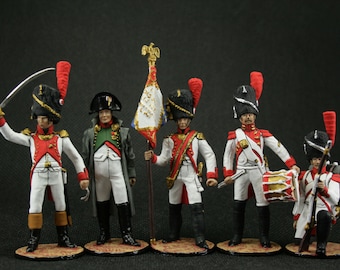 Peut inclure: Cinq soldats de jouet peints à la main en uniformes militaires, dont un tambourinaire, un porte-drapeau et trois fantassins. Les soldats portent des uniformes blancs et rouges avec des chapeaux noirs et tiennent diverses armes et accessoires.