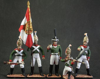 Peut inclure: Cinq soldats de jouet peints en uniforme vert et blanc avec des chapeaux noirs et des fusils. Les soldats sont debout sur une surface brune avec un drapeau blanc derrière eux.