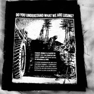 Puede incluir: Un parche en blanco y negro con el texto "DO YOU UNDERSTAND WHAT WE ARE LOSING?" y un gráfico de un vehículo conduciendo por un bosque. El texto debajo del gráfico habla sobre el cambio climático y su impacto en el medio ambiente.