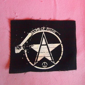 Op de afbeelding: Zwarte stoffen patch met witte tekst en een witte ster in een cirkel. De tekst luidt "Icons of Filth".