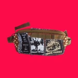 Riñonera táctica con parches anarquistas: Apatía nunca, Poder para el pueblo, "Exprésate", coche de policía en llamas