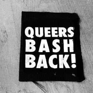 May include: Black and white patch with the text "Queers Bash Back!" in white letters.