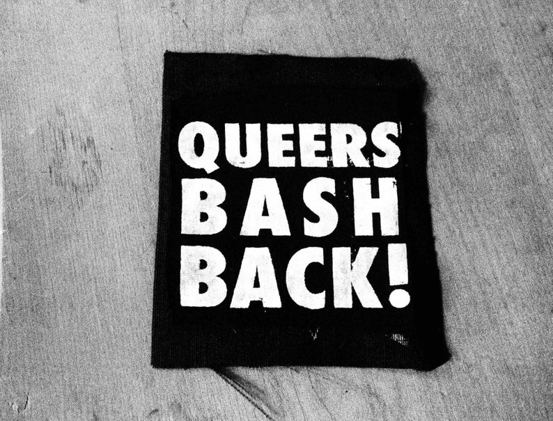 以下が含まれることがあります： 白黒のパッチで、白い文字で「Queers Bash Back!」と書かれています。