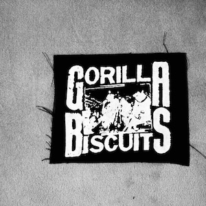 Könnte beinhalten: Schwarz-weiß-Patch mit dem Text "GORILLA BISCUITS" in weißen Buchstaben. Der Patch zeigt ein Schwarz-Weiß-Bild einer Band in der Mitte.