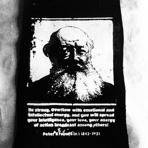 Può includere: Immagine in bianco e nero di Peter Kropotkin, un anarchico e rivoluzionario russo, con la citazione "Sii forte. Trabocca di energia emotiva e intellettuale, e diffonderai la tua intelligenza, il tuo amore, la tua energia d'azione tra gli altri! Peter Kropotkin 1842-1921".
