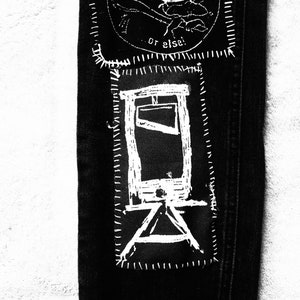 Puede incluir: Vaqueros negros de denim con un diseño de guillotina bordado en blanco. El diseño incluye el texto "or else!"