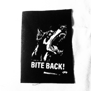 Könnte beinhalten: Schwarz-weiß-Patch mit einem knurrenden Hund und dem Text "BITE BACK!"