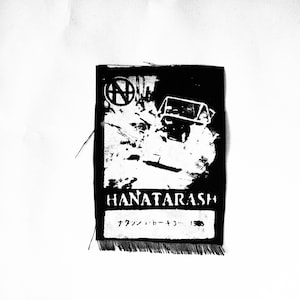 May include: Black and white embroidered patch with the text "HANATARASH" and Japanese text. The patch features a stylized image of a car driving through a snowy landscape.