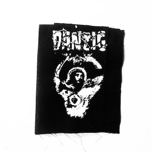 Może przedstawiać: Czarno-biała naszywka do prasowania z napisem "DANZIG" w stylu vintage i grafiką czaszki z aureolą.