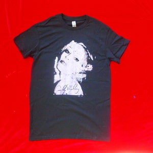 Puede incluir: Camiseta negra con una imagen en blanco y gris de la cara de una mujer y la firma "Candy Darling".