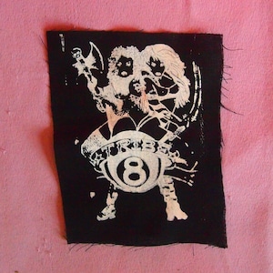 May include: Black and white patch featuring two figures holding a white 8-ball with the word "TRIBE" around it.