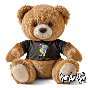 May include: A brown teddy bear wearing a black t-shirt with the word "SNOOPY" in colorful letters. The bear has a soft, plush appearance and is sitting upright. The bear's fur is a light brown color, and it has a brown nose and black eyes.