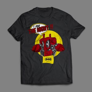May include: Black t-shirt featuring a comic book style graphic. The design includes a figure with red gloves and a speech bubble that reads "I AM THE NIGHT!!" with a yellow circle and a Batman logo.