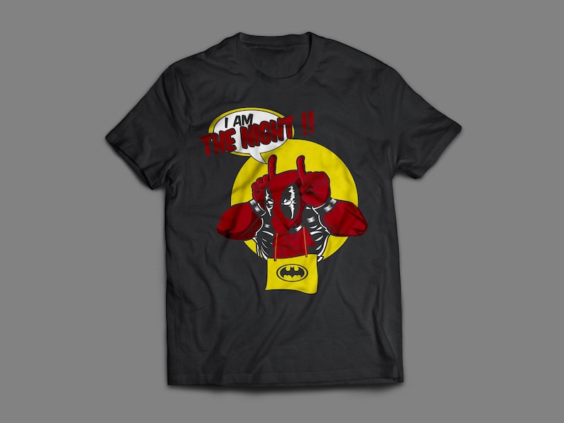 May include: Black t-shirt featuring a comic book style graphic. The design includes a figure with red gloves and a speech bubble that reads "I AM THE NIGHT!!" with a yellow circle and a Batman logo.