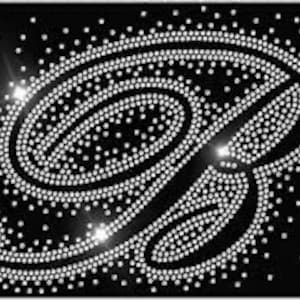 May include: A large, silver rhinestone design of the letter "B" on a black background.