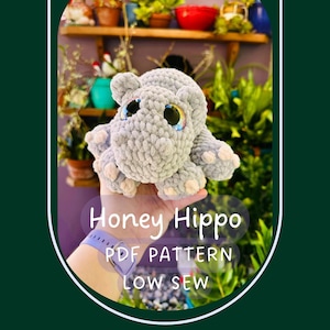 May include: A light gray crocheted hippo plush toy with large, dark, reflective eyes and light pink accents on the feet. The image includes the text Honey Hippo PDF PATTERN LOW SEW, indicating a digital pattern for creating this stuffed animal.