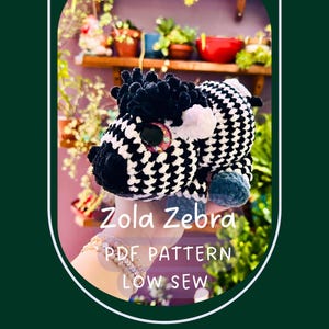 May include: A handmade crochet zebra toy with black and white patterned body, black mane, and large, glittery eyes. The text "Zola Zebra PDF PATTERN LOW SEW" is displayed on the image. This soft toy is a unique, handcrafted item.