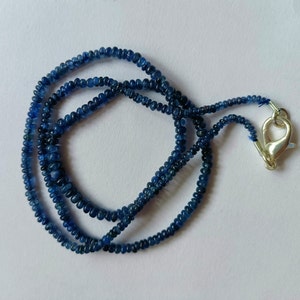 Puede incluir: Una hebra de cuentas de piedras preciosas azules con un cierre de plata. Las cuentas son pequeñas y redondas, y la hebra mide aproximadamente 45 cm de largo.