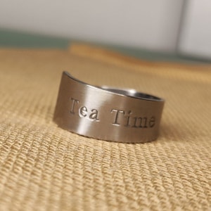 Peut inclure: Une bague en argent avec les mots "Tea Time" gravés dessus.