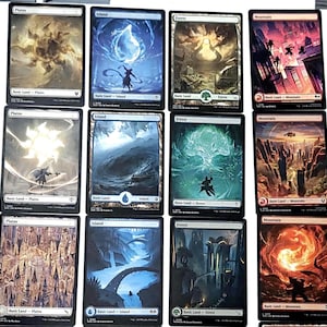 May include: A collection of twelve Magic: The Gathering trading cards arranged in a grid. The cards feature various artistic illustrations of plains, islands, forests, and mountains, each labeled with its respective basic land type and mana symbol.