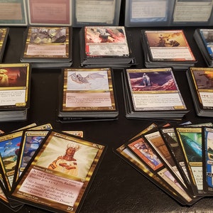 May include: A collection of Magic: The Gathering cards, featuring various illustrations and card names. The cards are organized into stacks and spread out on a dark surface.