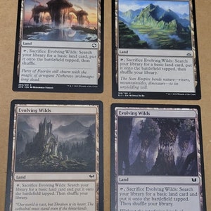 May include: Four Magic: The Gathering cards featuring the land card "Evolving Wilds". Each card has a different illustration of a landscape with a quote about the card's ability.
