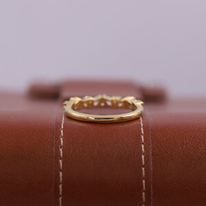 Pu&ograve; includere: Un anello con fascia in oro con piccole pietre trasparenti incastonate nella fascia.