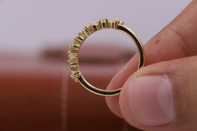 Pu&ograve; includere: Un anello a fascia d'oro con una fila di piccole pietre preziose trasparenti.