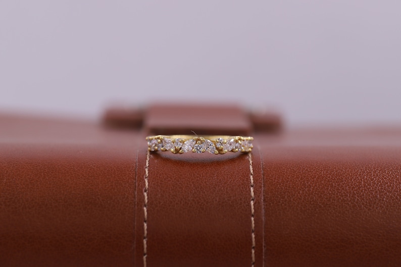 Pu&ograve; includere: Un anello a fascia d'oro con una fila di piccole pietre preziose trasparenti.