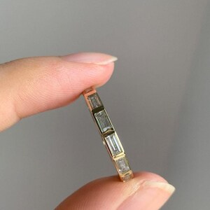 May include: A gold band ring with five baguette-cut diamonds set in a row.