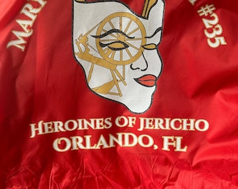 May include: Red jacket with the text "MARY L. SMITH COURT #235 HEROINES OF JERICHO ORLANDO, FL" embroidered in white and gold. The jacket features a white and gold graphic of a woman's face with a spinning wheel.