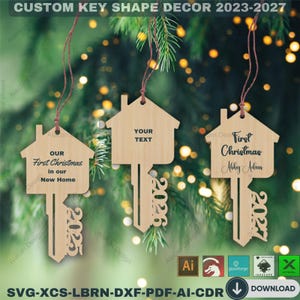 Op de afbeelding: Houten kerstversieringen in de vorm van een sleutel. Elke versiering heeft een huisvormige bovenkant en een sleutelvormige onderkant met het jaar 2025, 2026 of 2027. Eén leest "Our First Christmas in our New Home". Een andere zegt "First Christmas Abby Adam".