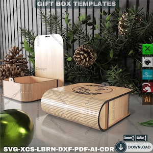 Puede incluir: Tres plantillas de cajas de regalo de madera con un acabado de madera natural. Una caja está abierta, otra está cerrada y la tercera es una tapa. Las cajas están rodeadas de vegetación y piñas. El texto "GIFT BOX TEMPLATES" está en la parte superior.