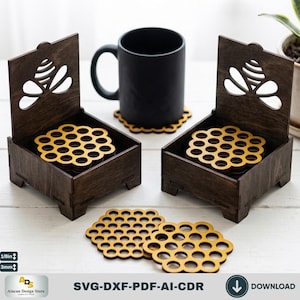 Peut inclure: Deux boîtes en bois brun foncé avec des couvercles à charnières présentant un motif d'abeille découpé au laser, contenant chacune une pile de sous-verres jaunes en nid d'abeille. Un mug noir repose sur un sous-verre assorti.