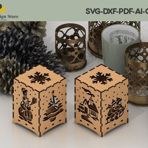 K&ouml;nnte beinhalten: Zwei Kerzenhalter aus Holz mit filigranen Ausschnitten von Winterszenen. Einer zeigt einen Schneemann und einen Weihnachtsbaum, der andere ein Haus und Kinder beim Schlittenfahren. SVG-DXF-PDF-AI-CDR.