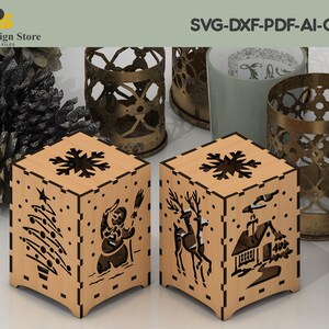 K&ouml;nnte beinhalten: Zwei Kerzenhalter aus Holz mit filigranen Ausschnitten von Winterszenen. Einer zeigt einen Schneemann, einen Weihnachtsbaum und Schneeflocken. Der andere zeigt ein Reh, ein Haus und Schneeflocken. SVG-DXF-PDF-AI-CDR