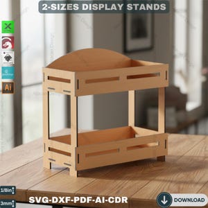 May include: A two-tiered display stand made of light brown wood. The stand has a rectangular base and two shelves. The text "2-SIZES DISPLAY STANDS" is at the top. The bottom of the image has the text "SVG-DXF-PDF-AI-CDR".