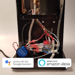 May include: A black electronic device with visible internal components, including wires, tubes, and a copper pipe. The device has a blue component with text and two white rectangles with the text "works with the Google Assistant" and "works with amazon alexa".