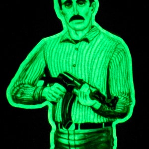 May include: A green-toned illustration of a man holding a rifle, set against a black background. The man is wearing a striped shirt and has a mustache. The image has a glowing effect, giving it a unique visual style.