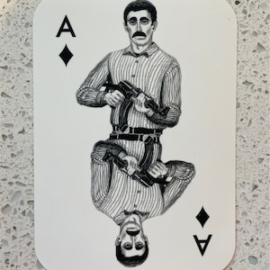 May include: Ace of Diamonds playing card featuring a black and white illustration of a man holding a machine gun. The card has the letter "A" and a diamond symbol in the corners.
