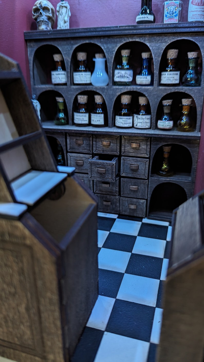 May include: A wooden apothecary cabinet with multiple drawers and shelves. The shelves are filled with small glass bottles with labels. The cabinet is in a room with a black and white checkered floor.
