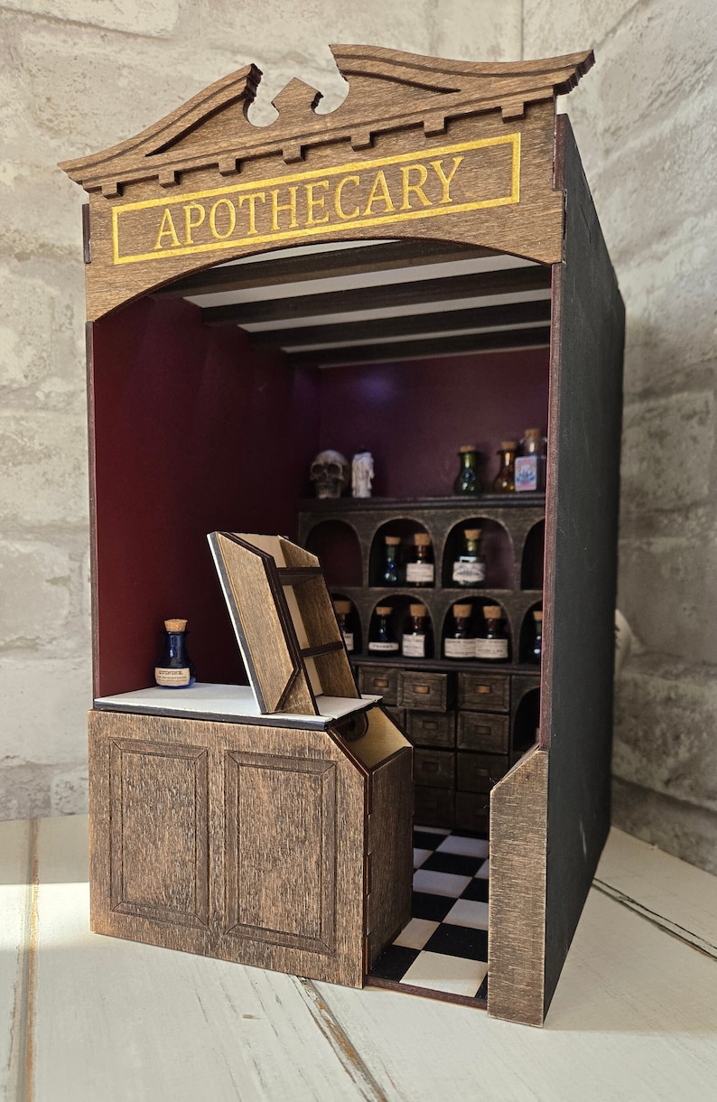 May include: A miniature wooden apothecary shop with a sign that reads "APOTHECARY" in gold lettering. The shop has a dark wood counter, shelves filled with small glass bottles, and a checkered floor.