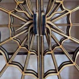Puede incluir: Un par de puertas de madera con un dise&ntilde;o de telara&ntilde;a. Las puertas est&aacute;n hechas de madera fina y en capas y tienen un borde pintado de negro. Las puertas est&aacute;n cerradas y el dise&ntilde;o es sim&eacute;trico.
