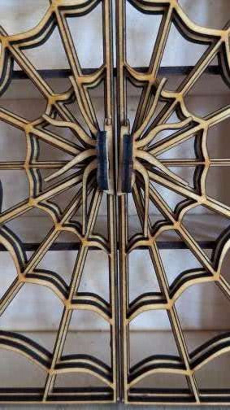 Puede incluir: Un par de puertas de madera con un dise&ntilde;o de telara&ntilde;a. Las puertas est&aacute;n hechas de madera fina y en capas y tienen un borde pintado de negro. Las puertas est&aacute;n cerradas y el dise&ntilde;o es sim&eacute;trico.
