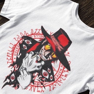 Puede incluir: Camiseta blanca con un estampado gráfico rojo y negro de un personaje con un sombrero rojo y múltiples ojos. El gráfico está rodeado de un círculo rojo con el texto "HELLS GATE" e "INVICTED" en rojo.